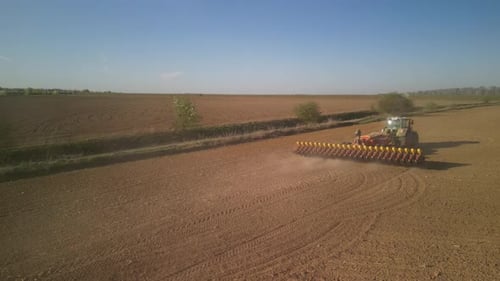 Green tractor works on the field sowing sunflower. Tractor planting corn in Ukraine