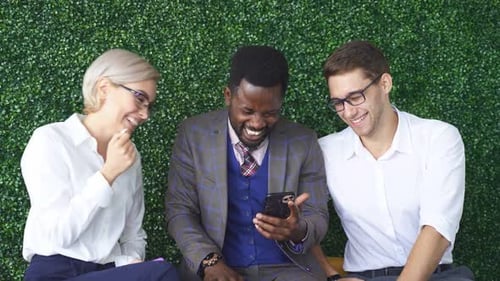 Man Shows His Colleagues in Office a Funny Video on a Smartphone