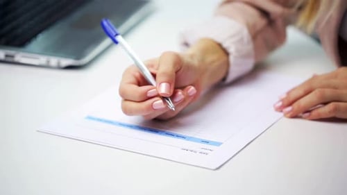 Woman fills out form while at desk