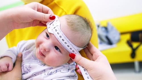Doctor Measures Adorable Infant's Head in Clinic