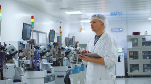 Weißer Techniker inspiziert Halbleiterfertigungslinie und untersucht Dioden und Mikrochips unter