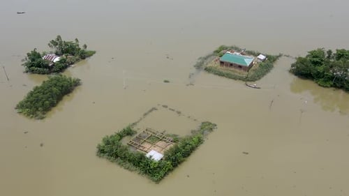 Aerial view over boat leaving flood affected submerged village home in Bangladesh community