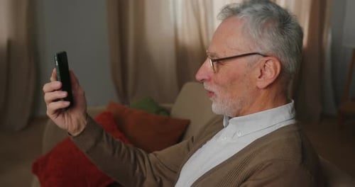 Senior Man Video Calling at Home on Cellphone