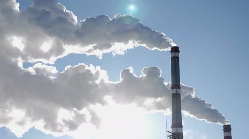 Industrial Chimneys Releasing Smoke Against Blue Sky