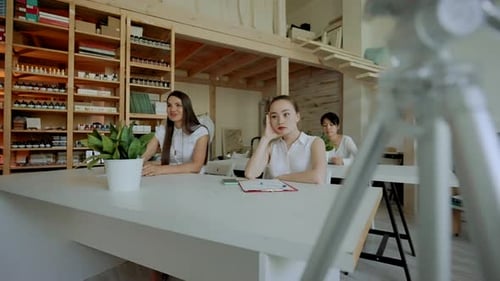 Tripod with Camera Stands Against Students Sitting at Desks