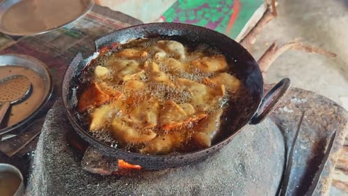 Nahaufnahme — brutzelnde Samosas, die auf einem traditionellen Herd in Öl gebraten werden und Blasen, Hitze und Goldbarren zeigen
