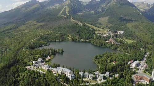 Tilt Up Drone Shot Alpine Lake and Resorts on Mountainside, High Tatras Slovakia