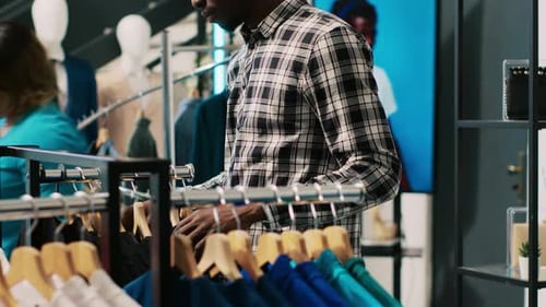 Man Browsing Clothing Rack in Boutique Store