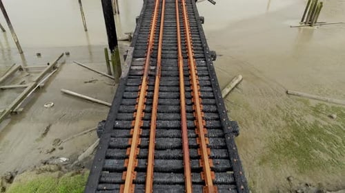 Trilhos de trem carbonizados se estendem sobre o leito lamacento do rio em Richmond, Colúmbia Britânica, Canadá - Drone
