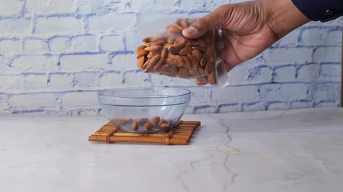 Pouring Almonds Into Bowl in Kitchen