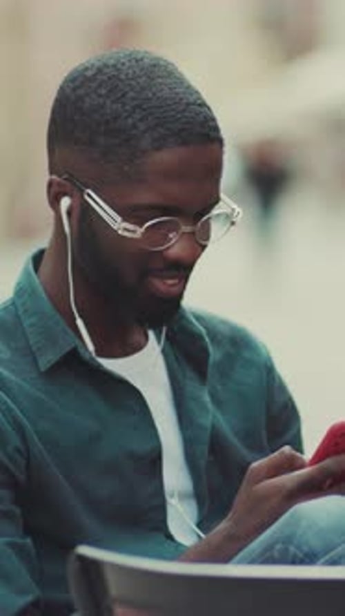 Young Adult Using Cell Phone at Outdoor Cafe