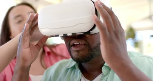 Anpassung des VR-Headsets, Frau hilft afroamerikanischem Mann, virtuelle Realität zu Hause zu erleben