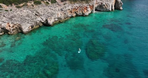 Tourist auf SUP-Board paddelt im wunderschönen türkisfarbenen Meer AERIAL ORBIT