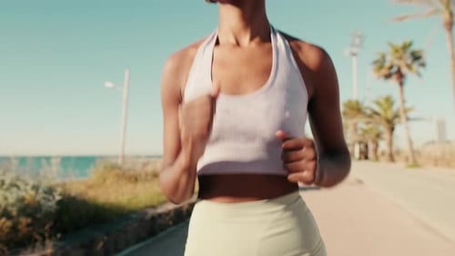 Close-up of smiling girl in sportswear and with headphones jogging outdoors