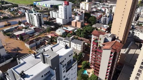 City buildings and green areas partially submerged in flood water, aerial