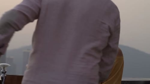 Young couple raising cocktails in a terrace bar with a beautiful city view