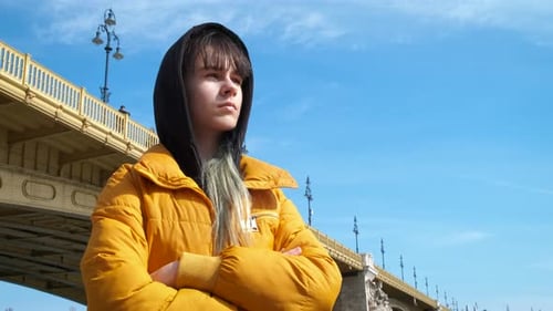 Woman in Yellow Jacket Near an Urban Bridge