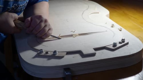 Luthier carefully carving new cello back plate wood for a new violoncello instrument