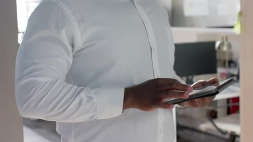 Portrait of happy african american businessman using tablet in sunny office, smiling, slow motion