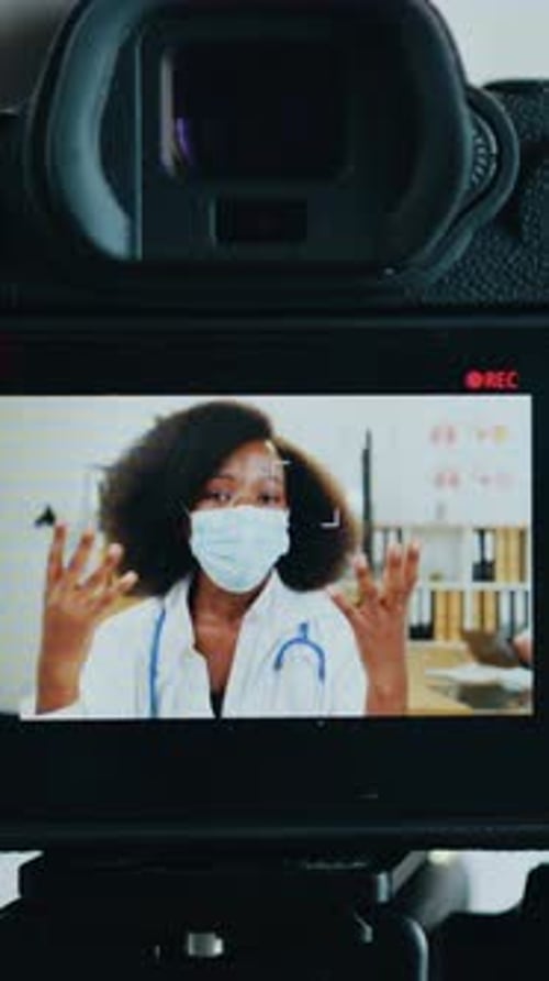 View Through Professional Camera on African American Woman Doctor in Protective Mask During