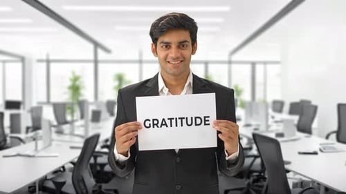 Happy Indian manager holding GRATITUDE banner