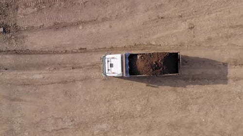 Large Truck hauling a full load of Excavated Soil on a dirt road.