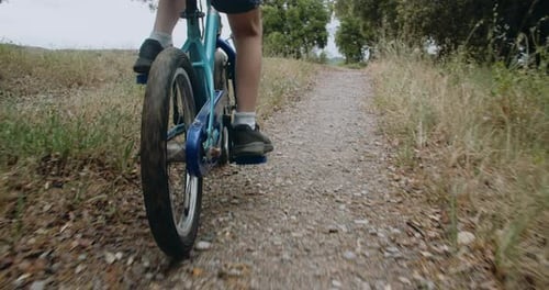 Child Boy Riding Bicycle in Forest Path at Rainy Day Slow Motion Following Shot