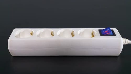 Hand Plugs Cord Into White Power Strip