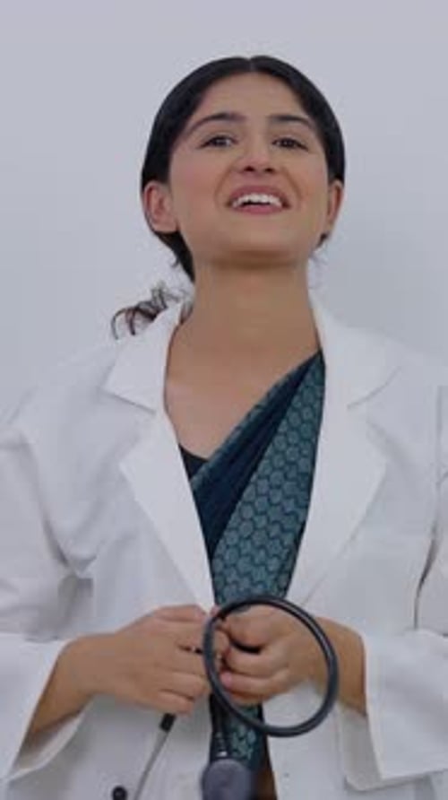 Vertical Video of Happy Indian Female Doctor Removing Stethoscope and Talking to Camera