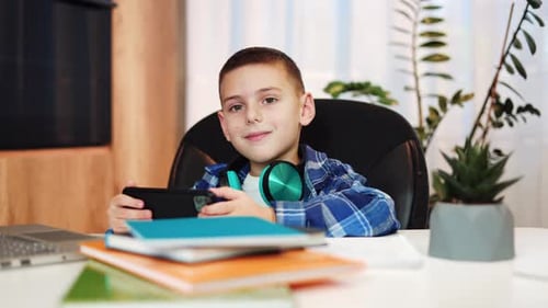 Boy Using Smartphone with Headphones at Desk