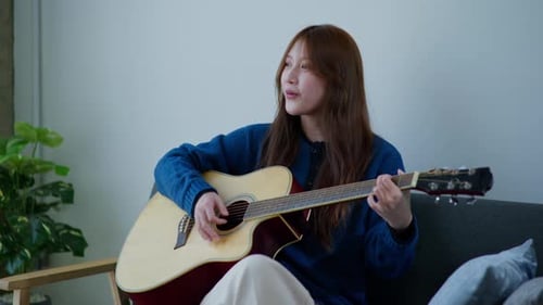 Woman Plays Guitar and Sings at Home