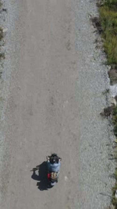 Aerial View of a Motorcyclist Riding on a Dusty Suburban Road