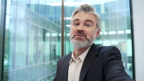 POV Smiling businessman talking on a video call using phone in modern office. Male entrepreneur