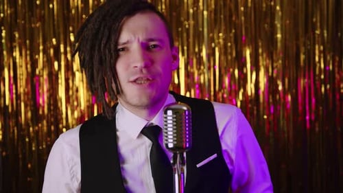 A White Male Hiphop Singer with Dreadlocks in White Shirt Black Vest and Tie Reads Rap Into a