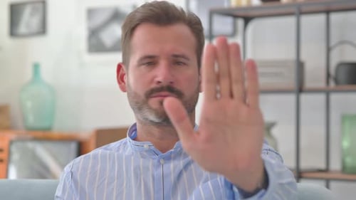 Portrait of Middle Aged Man with Stop Gesture Sitting at Home