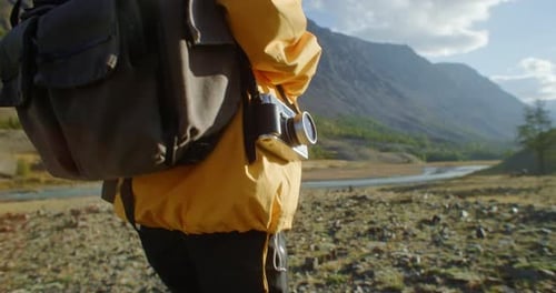 Photographe faisant de la randonnée dans les montagnes avec un appareil photo vintage et un sac à dos