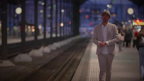Man in Fedora Walks on Train Platform at Night