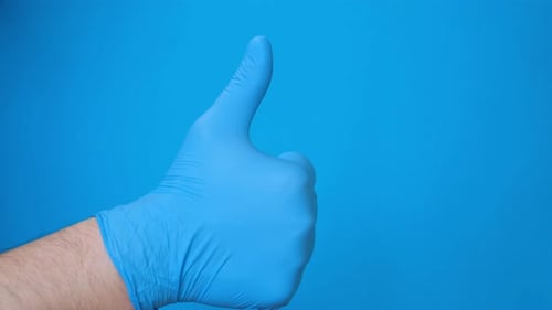 Thumbs Up with Blue Medical Glove on Blue Background