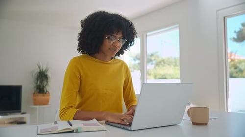 Woman Working on Laptop at Bright Home Workspace