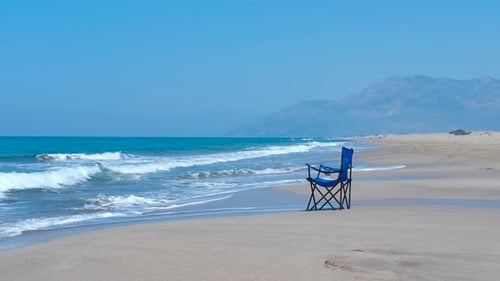 Waves Crashing Against an Isolated Beach Chair on a Serene Shoreline