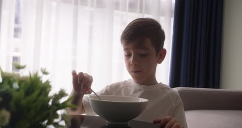 A Handsome Cute Child is Eating Porridge The Child Eats Porridge and Plays a Family Dinner in the