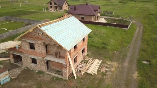 Aerial View of a Brick House with Wooden Roof Frame Under Construction