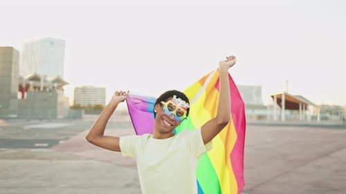 Smiling Person Holding Pride Flag in Sunlight
