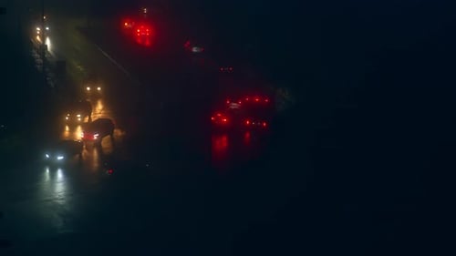 Two-way road with cars moving slowly along. Dark street with only headlights from vehicles