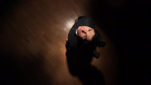 Man Lies on Wood Floor and Looks Upward