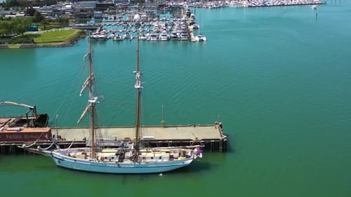 Historic Tall Sailing Ship Docked in Vibrant Turquoise Harbor Marina Waters