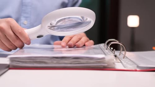 Accountant Examining Documents with Magnifying Glass in Office