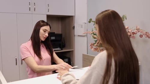 Receptionist Helping Patient Sign In At Clinic
