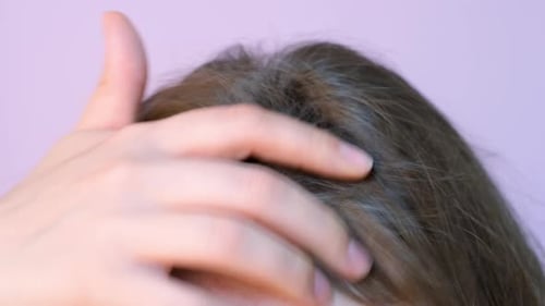 Girl touching her hair close-up on light pink background, hair loss concept.