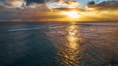 Fantastic sunset over the ocean waterscape. Rainy clouds are gathered in the sky above the scenery